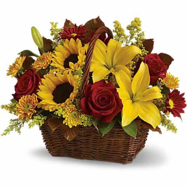 Basket arrangement with yellow lilies, sunflowers, and red roses