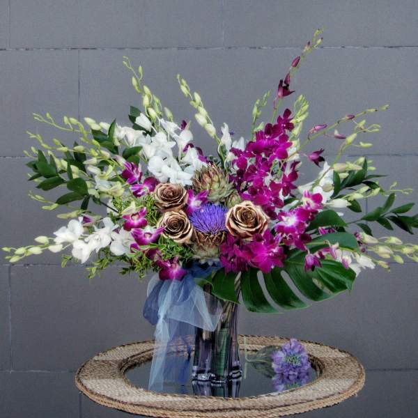 Bouquet of white and purple orchids with roses in a glass vase