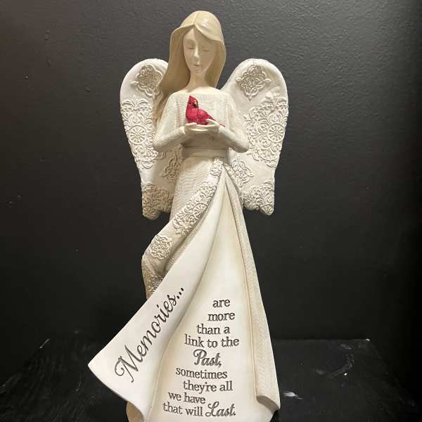 White angel figurine holding a red bird with a memorial message on the robe