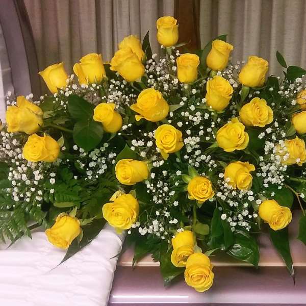 Yellow roses arranged in a large casket spray with baby's breath
