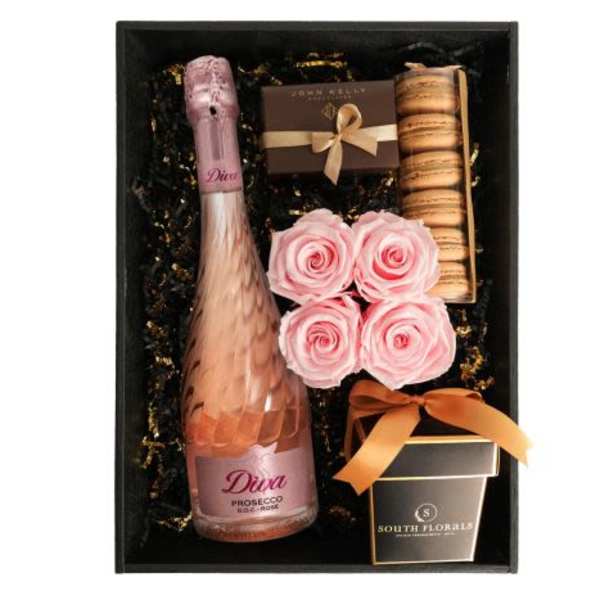 Gift box with pink sparkling wine, pink roses, macarons, and chocolates