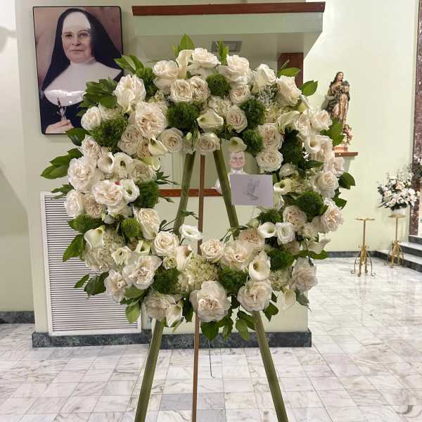 Large white floral wreath on an easel in a church interior