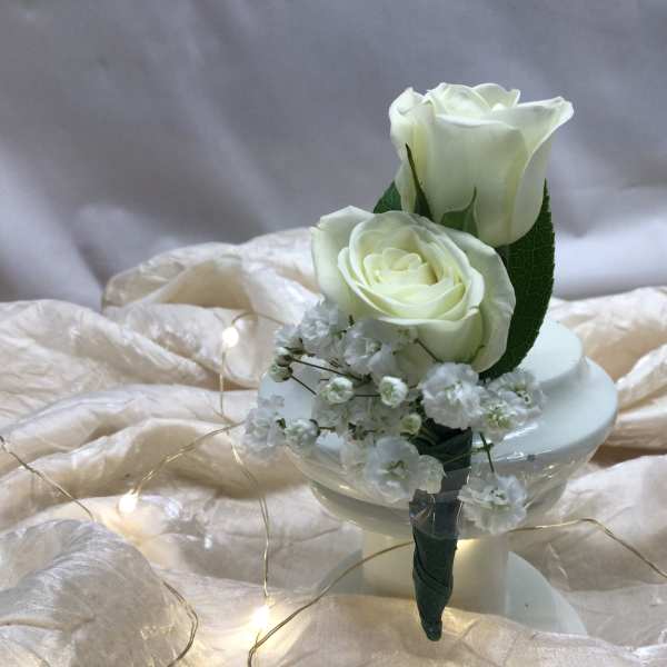 Two white roses with baby's breath in a small holder