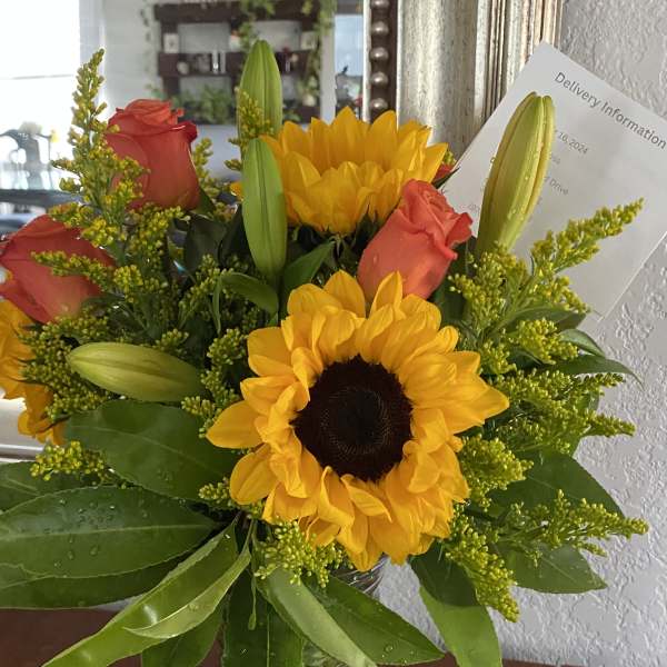 Sunflowers and red roses in a clear glass vase