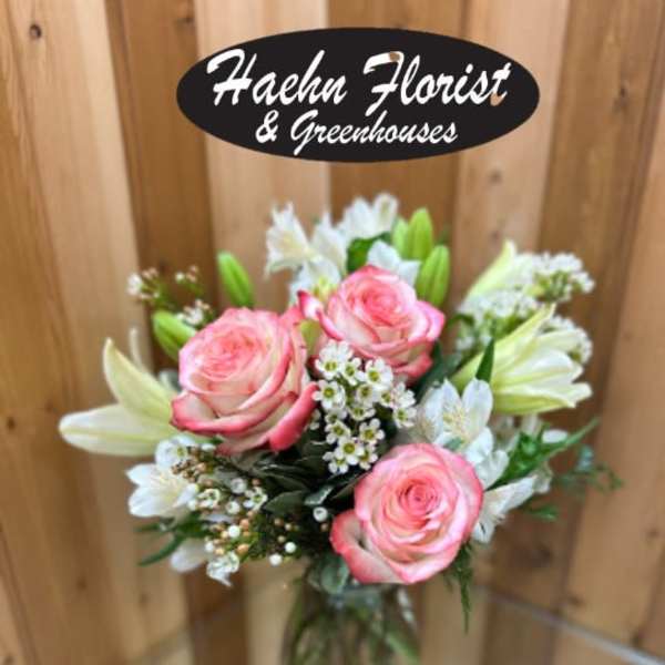 Pink roses and white lilies in a clear glass vase