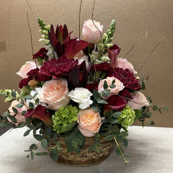 Basket arrangement of pink and burgundy flowers with eucalyptus