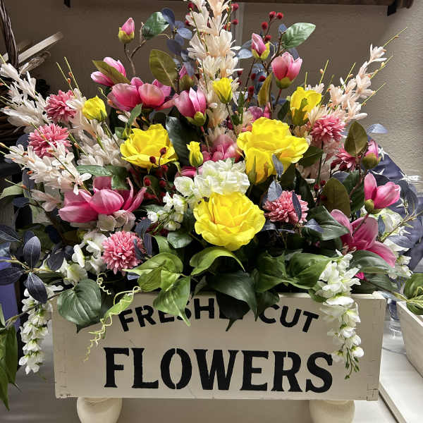 Bright mixed flower arrangement in a wooden box with pink, yellow, and white blooms