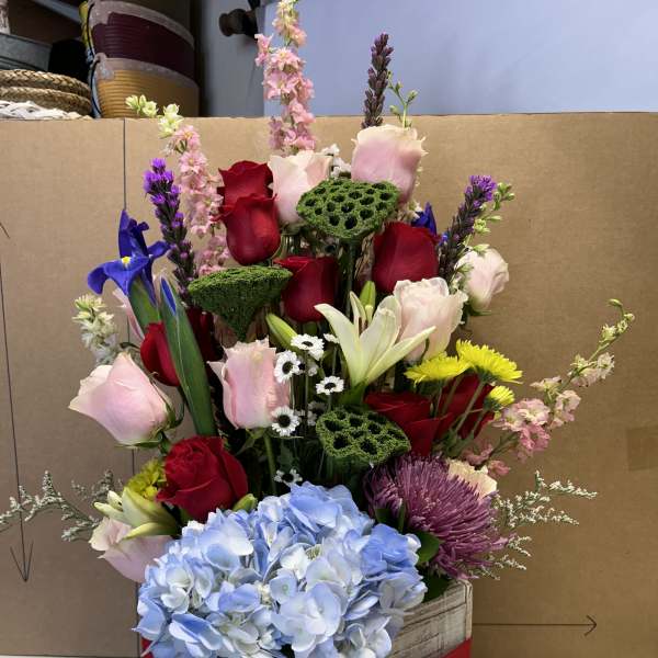 Mixed bouquet in a wooden box with roses, hydrangea, and lilies