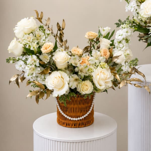 White and peach rose arrangement in a wicker basket with pearl trim