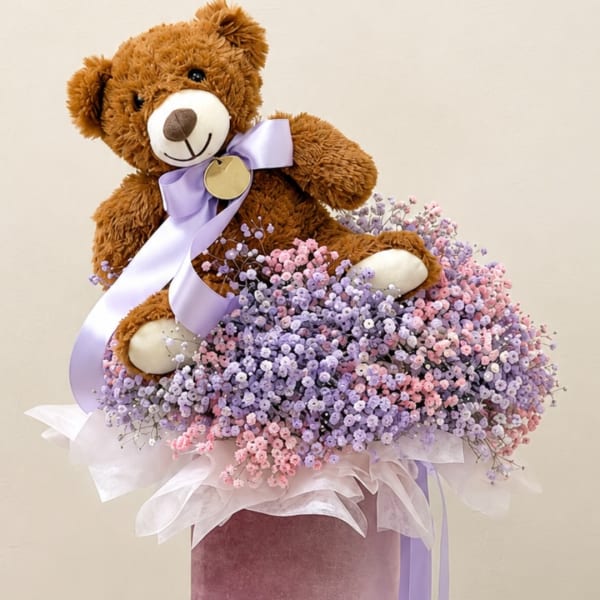 Teddy bear sitting in a pastel baby breath bouquet with a lavender ribbon