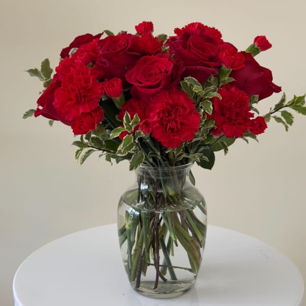 Red roses and carnations in a clear glass vase