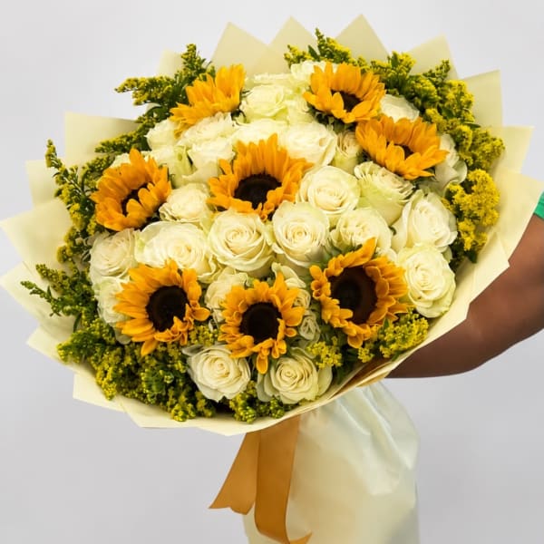 Bouquet of white roses and yellow sunflowers wrapped in pale paper