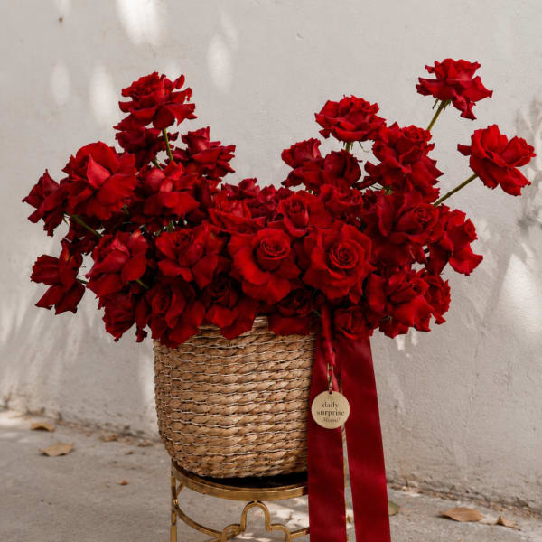 Basket of red roses with a red ribbon on a gold stand