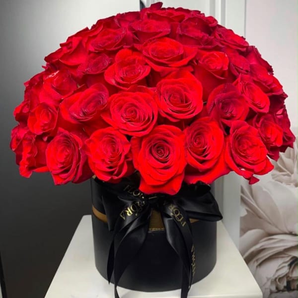Red roses arranged in a black round box with a black ribbon