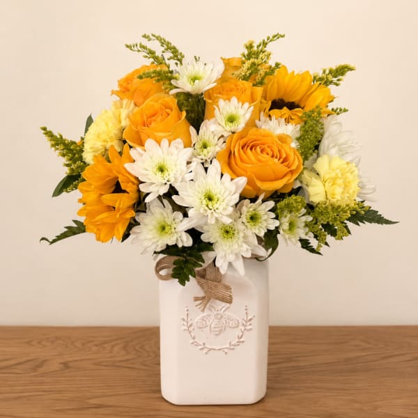 Yellow and white flower arrangement in a white ceramic vase