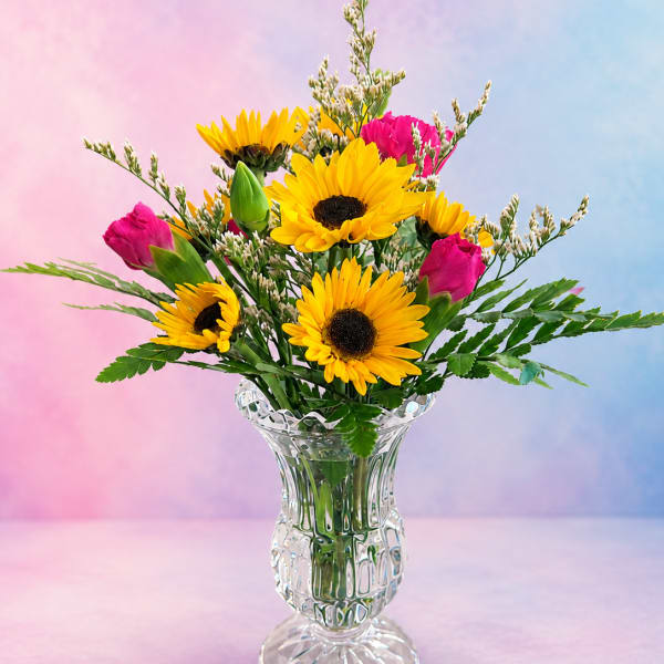 Yellow sunflowers and pink roses in a clear glass vase