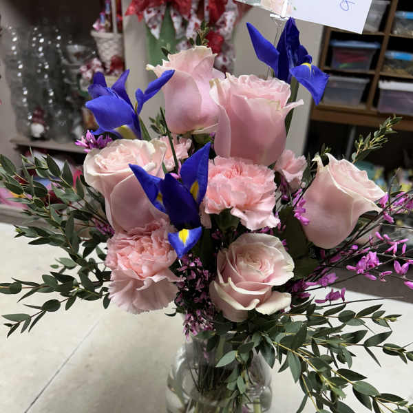 Pink roses and carnations with blue irises in a glass vase