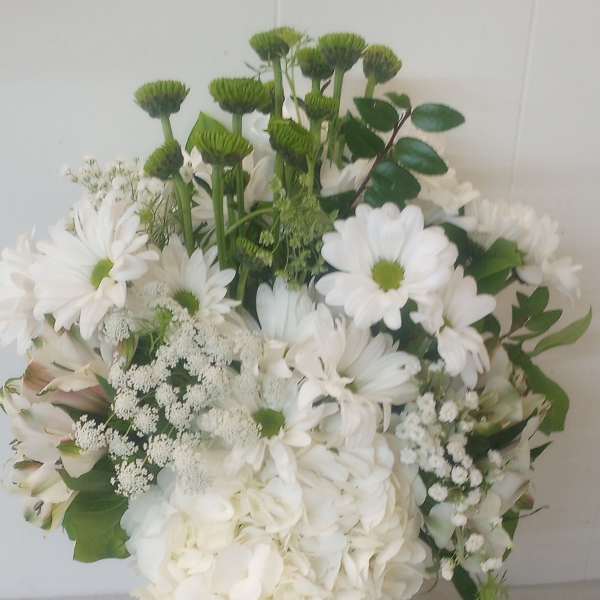 White bouquet with daisies, hydrangea, and green button mums in a glass vase