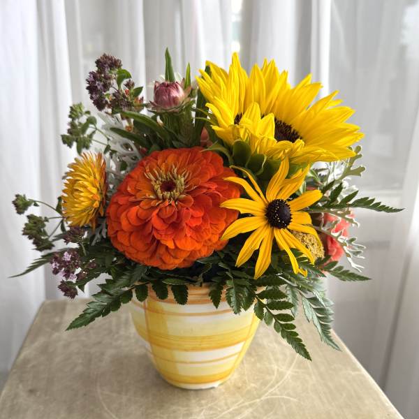 Bright yellow and orange flowers arranged in a striped ceramic vase