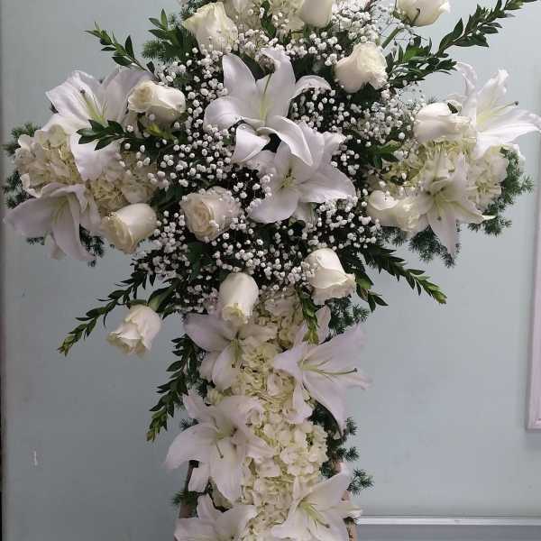 Large white floral cross arrangement with lilies and roses