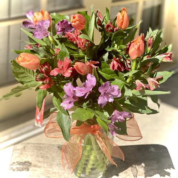 Bouquet of orange tulips and purple alstroemeria in a glass vase