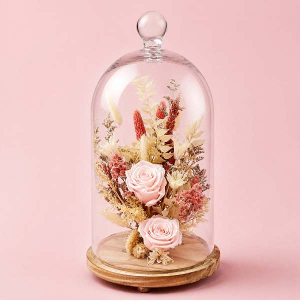 Pink roses under a glass dome on a wooden base