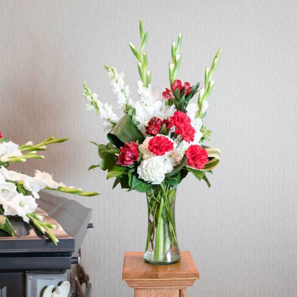 Tall red and white floral arrangement in a clear glass vase