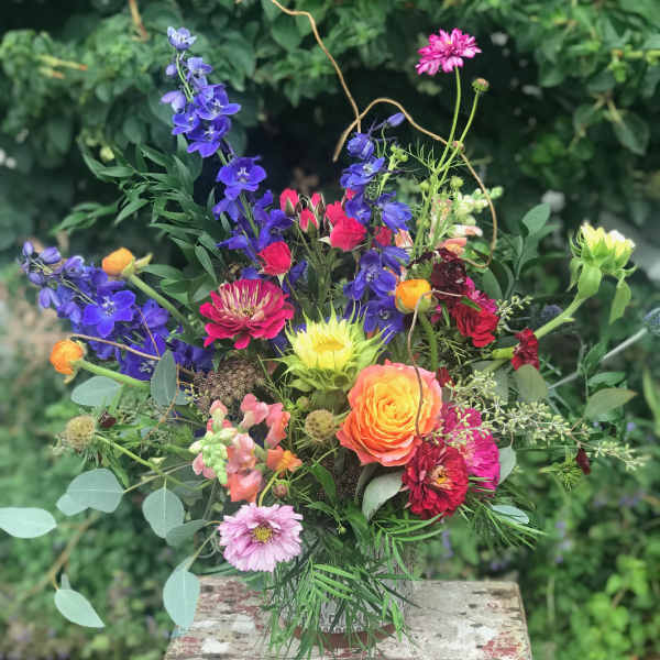 Mixed bouquet with bright blue, pink, orange, and yellow flowers in a vase