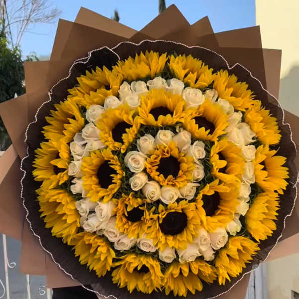 Large bouquet of yellow sunflowers and white roses wrapped in brown paper
