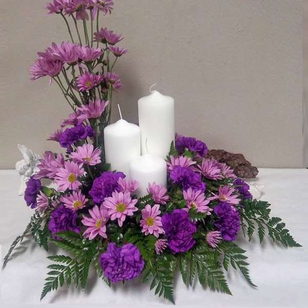 Purple and pink floral centerpiece with three white candles