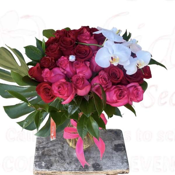 Bouquet of red and pink roses with white orchids in a glass vase