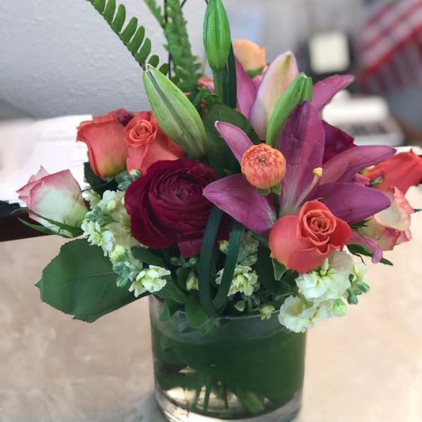Mixed bouquet of pink roses and purple lilies in a glass vase