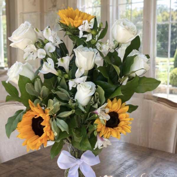 Bouquet of white roses, white alstroemeria, and sunflowers in a glass vase