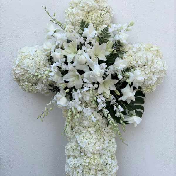 White floral cross arrangement on an easel