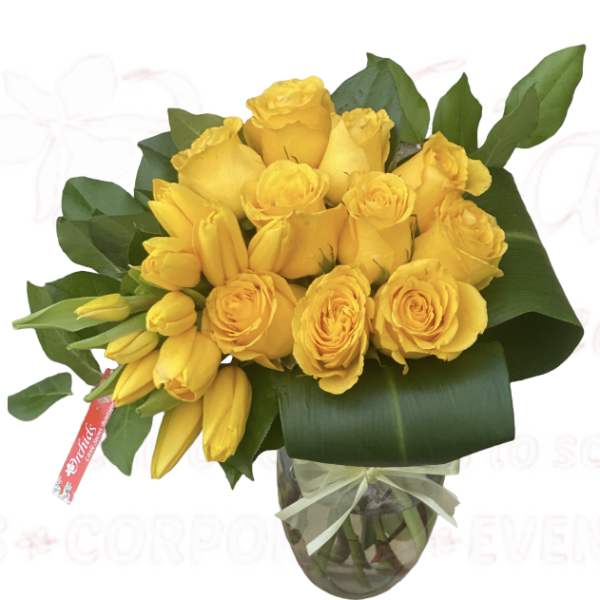 Yellow roses and lilies arranged in a glass vase