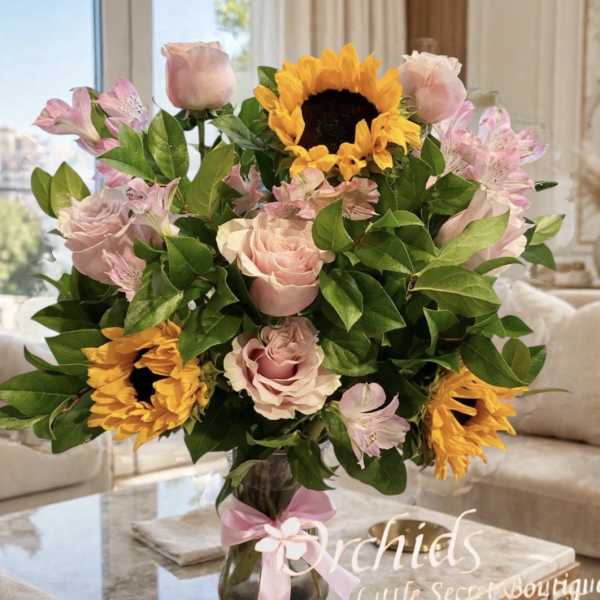 Bouquet of pink roses, sunflowers, and alstroemeria in a glass vase