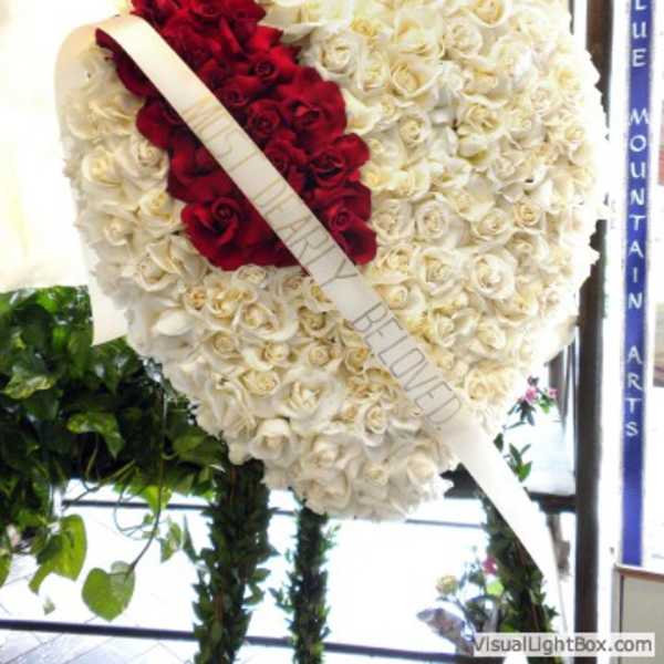 Heart-shaped rose wreath with red and white roses and a diagonal ribbon