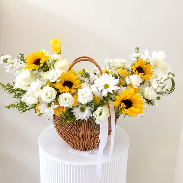 Basket of white and yellow flowers with a white ribbon