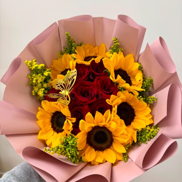 Bouquet of red roses and yellow sunflowers wrapped in pink paper