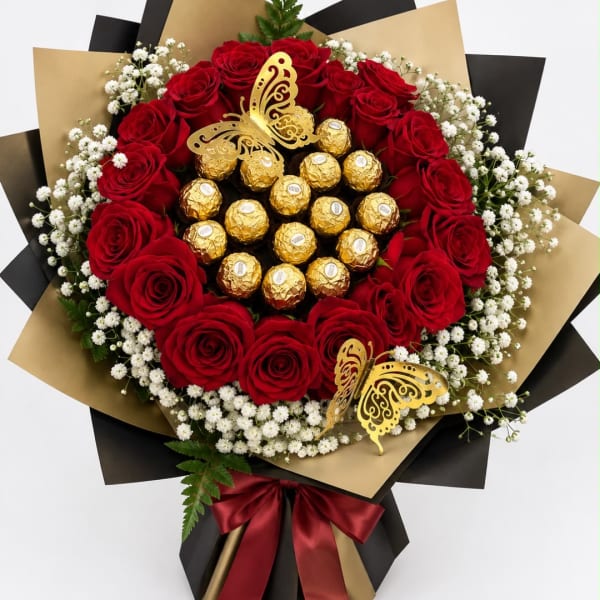 Red roses arranged with white baby's breath and gold chocolates, wrapped in black and gold paper