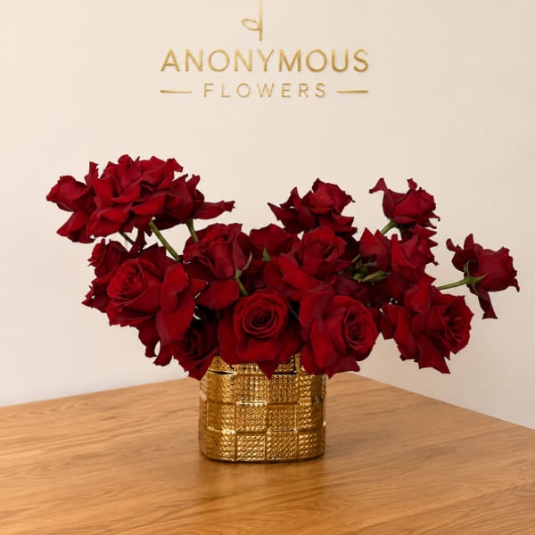 Red roses arranged in a gold textured vase on a wooden table