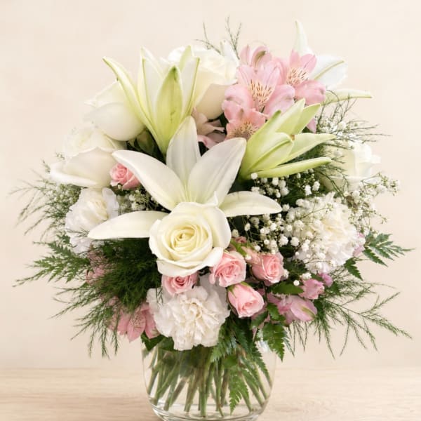 White lilies and roses with pink flowers in a glass vase