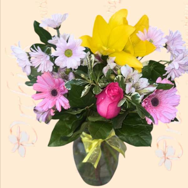Bouquet of pink and lavender daisies with a yellow lily in a vase