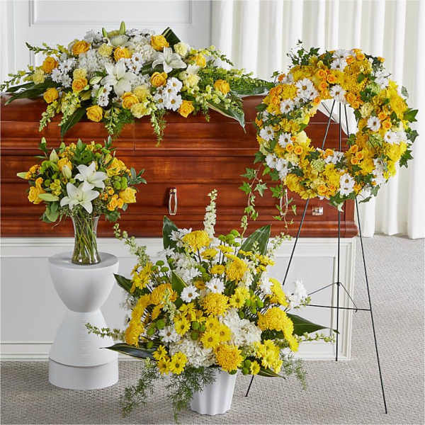 Yellow and white funeral floral arrangements around a casket