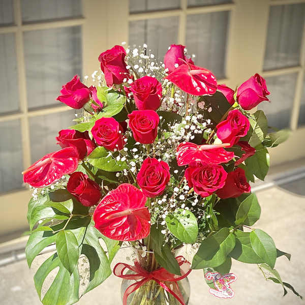 Red roses and anthuriums in a glass vase with baby's breath