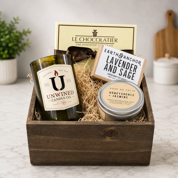 Gift basket with candles, soap, and chocolates in a wooden crate