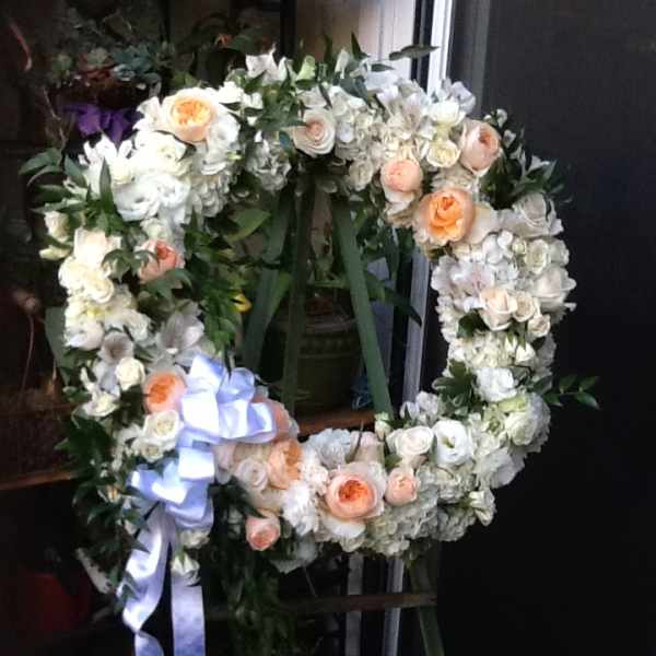 Heart-shaped floral wreath with white and peach roses and a lavender ribbon