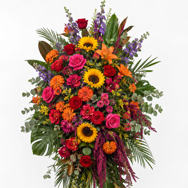 Tall standing floral spray with roses, sunflowers, lilies, and mixed blooms