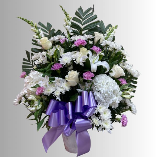 White and pink mixed flower arrangement in a vase with a purple ribbon