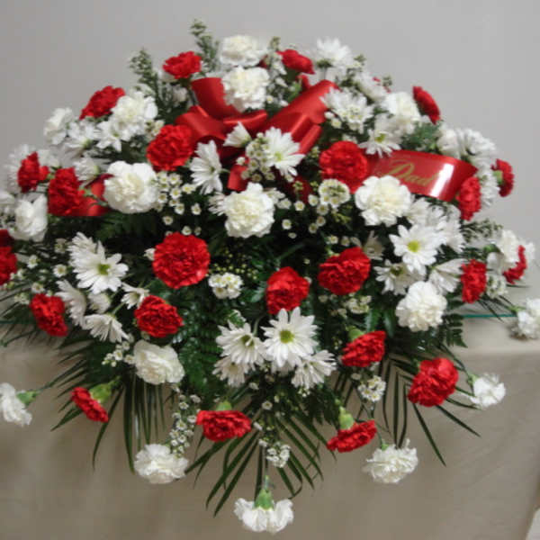 Red and white floral spray with ribbon on a table